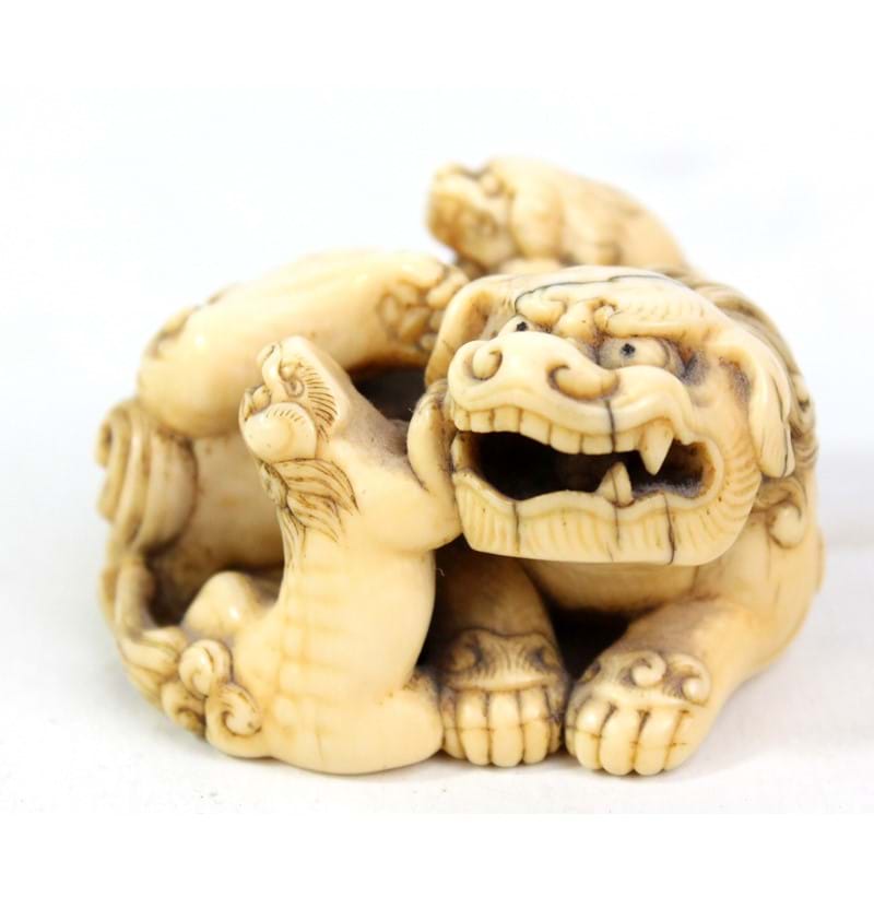 A Japanese Edo period carved ivory netsuke modelled as a chichi and two pups.